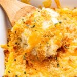 Closeup photo of a wooden spoon scooping out some of the Rosemary Cheddar Mashed Potato Casserole.