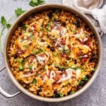 Overhead photo of metal skillet with a towel around the handle. Salsa chicken and cauliflower rice are in the skillet.