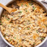 Overhead photo of Chickpea Noodle Casserole in a metal skillet with a wooden spoon in it.
