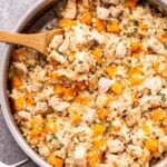Cheesy Chicken, Butternut Squash and Cauliflower Rice in a metal skillet with a wooden spoon in the skillet.