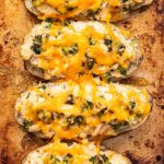 Four Broccoli cheddar chicken twice baked potatoes on a sheet pan.