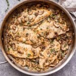 Creamy Mushroom Chicken breasts in a metal skillet with a dish towel around the handle of the skillet.