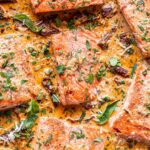 salmon fillets in a creamy sun dried tomato sauce with basil on top.