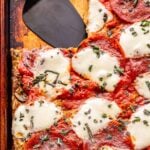 sheet pan pizza frittata with a square slice cut out of the top left corner.