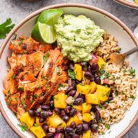 Southwest Salmon Rice Bowls with mango black bean salsa and guacamole in a white bowl.