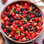 Berry Fruit Salad made with blueberries, blackberries, raspberries, strawberries in a white bowl. Tossed in honey lime dressing and topped with mint.