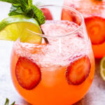 Strawberry Lime Vodka Smash with strawberry slices in the cocktail and a lime slice and mint sprig for garnish.