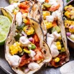 Two Grilled Salmon Tacos with Corn Salsa on a gray plate.