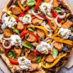 Overhead photo of Grilled Sausage and Peppers Pizza on a piece of parchment paper.