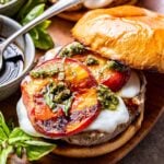 Peach Caprese Burger topped with fresh mozzarella, grilled peach slices, pesto and balsamic glaze. The top of the bun is halfway off the burger.