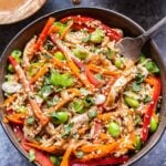 Gray bowl with Sesame Chicken Noodles topped with red bell peppers, shredded carrot and edamame.