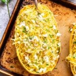 Half of a Spaghetti Squash with Feta and Herbs on a sheet pan with a fork in it