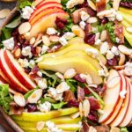 Autumn Apple and Pear Salad in a serving bowl with a jar of vinaigrette behind it.