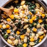 Butternut Squash, Sausage, and Kale Gnocchi Skillet with a wooden spoon in the skillet.