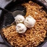 Pear Crisp in a cast iron skillet topped with vanilla ice cream.