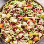 Shredded Brussels Sprouts Salad in a serving bowl with dressing behind the salad.