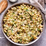 Brussels Sprouts and Ricotta Pasta in a skillet with a wooden spoon next to it and a bowl of grated parmesan behind it.
