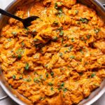 Easy Butter Chicken in a stainless steel skillet with a black serving spoon in the skillet.