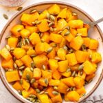 Hot Honey Roasted Butternut Squash topped with pepitas in a white serving bowl.