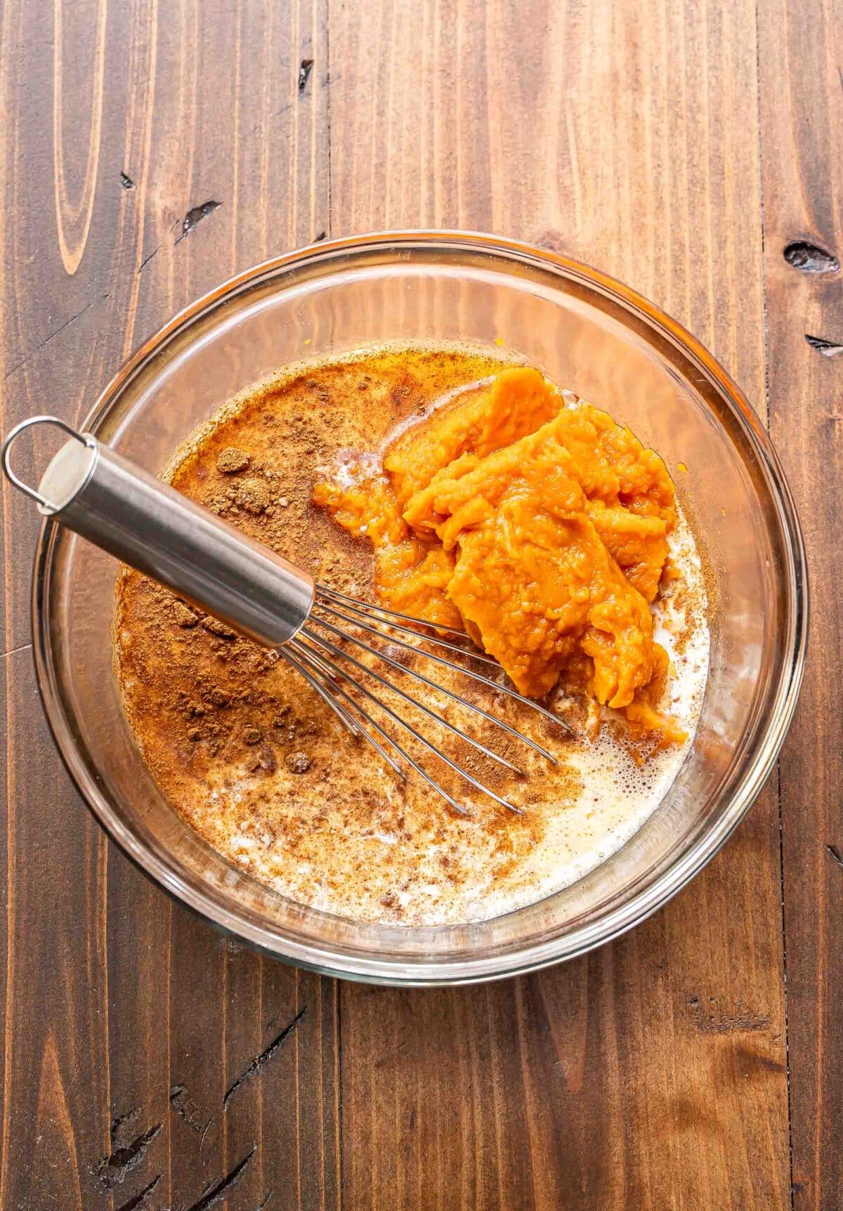 Pumpkin crisp filling in a glass bowl before being whisked together.