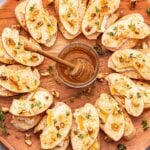 Apple Brie Crostini on a round serving platter with a jar of honey in the center.