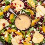 Christmas Salad on a round platter with a round bowl of vinaigrette in the center.