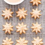 Cinnamon Spritz Cookies on a wire cooling rack with a bowl of glaze on the rack.