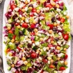 Mediterranean Chopped Salad on a white serving plate with vinaigrette behind it.