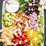 Barbecue Chicken Salad on a white plate with a bowl of greek yogurt ranch dressing.