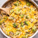 Broccoli Rice Casserole in a skillet with a wooden spoon in the skillet.