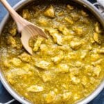Chicken Chile Verde in a stainless steel skillet with a wooden spoon in it.