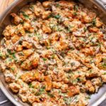 Chicken Stroganoff in a skillet with a wooden spoon next to it.