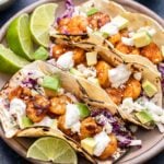 Three Shrimp Tacos with Creamy Slaw on a plate with lime wedges.