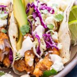 Grilled Fish Taco topped with cabbage, avocado, and white sauce.
