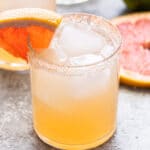 A paloma in a glass lined with salt and a grapefruit wedge.