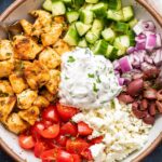 Chicken Gyro Bowl topped with cucumbers, olives, onion, tomatoes, feta, and tzatziki.
