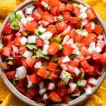 Pico de Gallo in a bowl with chips surrounding it.