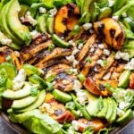 Grilled Chicken and Peach Salad with wooden serving spoons and a bowl of balsamic vinaigrette behind it.