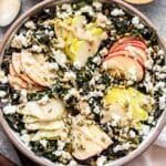 Apple and Kale Salad in a serving bowl. Topped with feta, pepitas, sunflower seeds and tahini dressing.