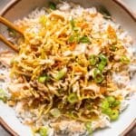 Egg roll in a bowl in a white bowl on top of rice with chopsticks.