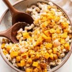 Butternut squash ricotta pasta in a white serving bowl with wooden spoons.
