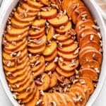 Bourbon Sweet Potatoes in a white oval casserole dish topped with pecans.