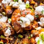 Closeup photo of Buffalo smashed Potatoes topped with blue cheese dressing, scallions, buffalo sauce, and blue cheese crumbles.