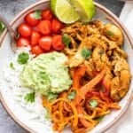 White bowl full of rice, chicken fajita meat, peppers, onions, tomatoes, and guacamole.