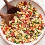 Mediterranean tuna salad in a white bowl with two wooden spoons.