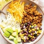 Ground chicken taco bowl filled with rice, ground chicken, avocado, cheese, and black bean corn salsa.