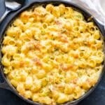 Baked green chile mac and cheese in cast iron skillet with a black serving spoon next to it.