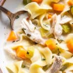 Closeup photo of creamy chicken noodle soup with a spoon.