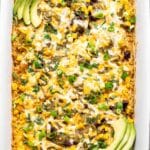 Southwest chicken casserole in a white rectangular dish topped with avocado slices.