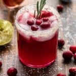 Cranberry margarita topped with fresh cranberries and a sprig of rosemary.